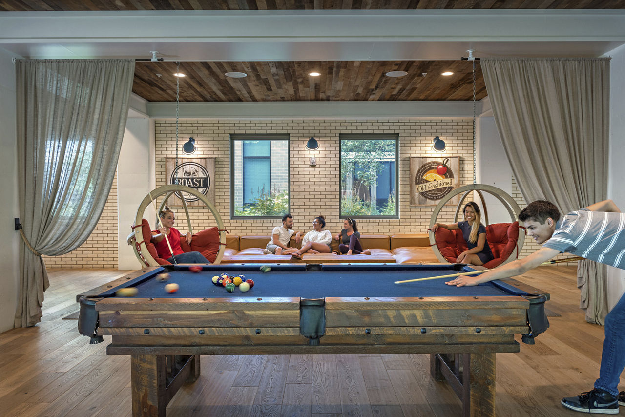Young adult playing pool in an amenity space | Blog | Greystar